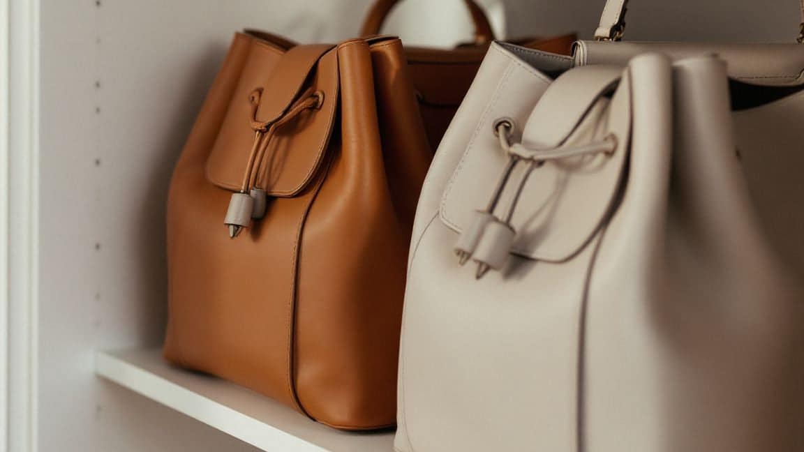 Leather handbags arranged on a closet shelf.